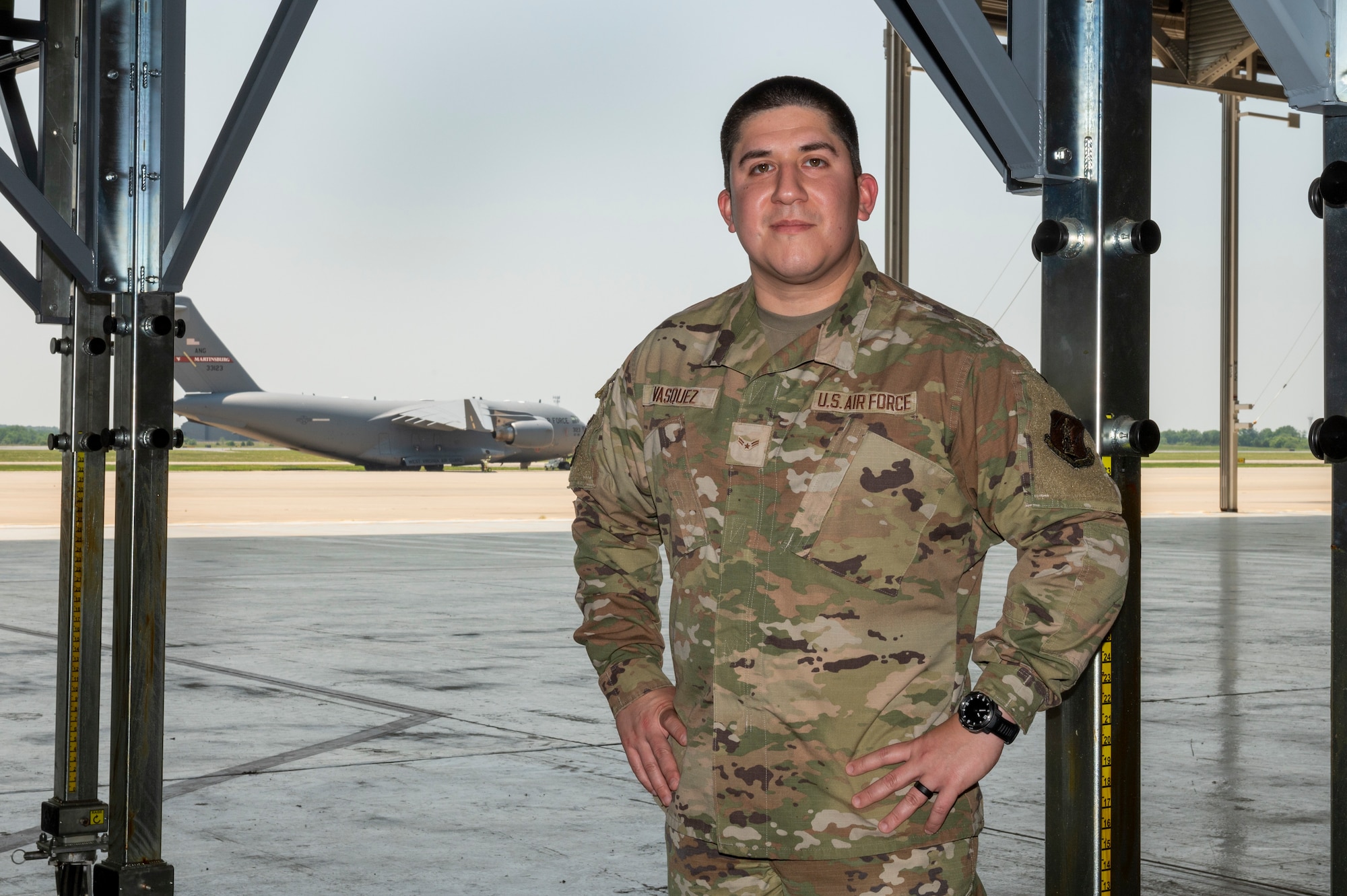a man stands in a hangar an aircraft is in the background