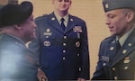 Two men wearing military uniforms shake hands.