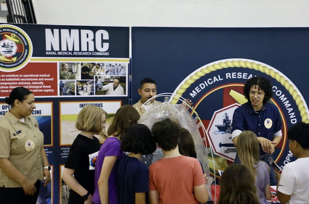 TAKOMA, Md. (June 09, 2025) Volunteers from Naval Medical Research Command (NMRC) engage with students at Piney Branch Elementary School about work done by and career opportunities in the Navy and in Medical Research. Piney Branch students had the opportunity to speak with active-duty Sailors and command scientists during the event. NMRC, headquarters of NMR&D, is engaged in a broad spectrum of activity from basic science in the laboratory to field studies in austere and remote areas of the world to investigations in operational environments. In support of Navy, Marine Corps and joint U.S. warfighter health, readiness and lethality, researchers study infectious diseases, biological warfare detection and defense, combat casualty care, environmental health concerns, aerospace and undersea medicine, operational mission support and epidemiology. For 250 years, Navy Medicine, represented by more than 44,000 highly-trained military and civilian healthcare professionals, has delivered quality healthcare and enduring expeditionary medical support to the warfighter on, below, and above the sea and ashore. (U.S. Navy photo by Elliott Page /Released)