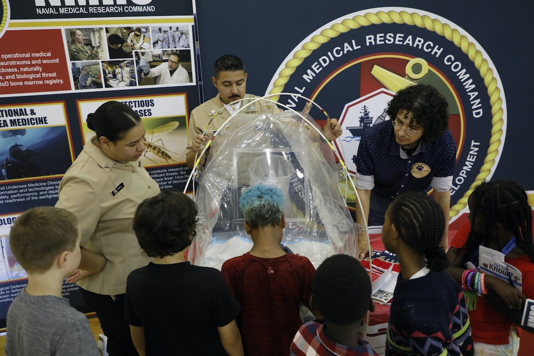 TAKOMA, Md. (June 09, 2025) Volunteers from Naval Medical Research Command (NMRC) engage with students at Piney Branch Elementary School about work done by and career opportunities in the Navy and in Medical Research. Piney Branch students had the opportunity to speak with active-duty Sailors and command scientists during the event. NMRC, headquarters of NMR&D, is engaged in a broad spectrum of activity from basic science in the laboratory to field studies in austere and remote areas of the world to investigations in operational environments. In support of Navy, Marine Corps and joint U.S. warfighter health, readiness and lethality, researchers study infectious diseases, biological warfare detection and defense, combat casualty care, environmental health concerns, aerospace and undersea medicine, operational mission support and epidemiology. For 250 years, Navy Medicine, represented by more than 44,000 highly-trained military and civilian healthcare professionals, has delivered quality healthcare and enduring expeditionary medical support to the warfighter on, below, and above the sea and ashore. (U.S. Navy photo by Elliott Page /Released)