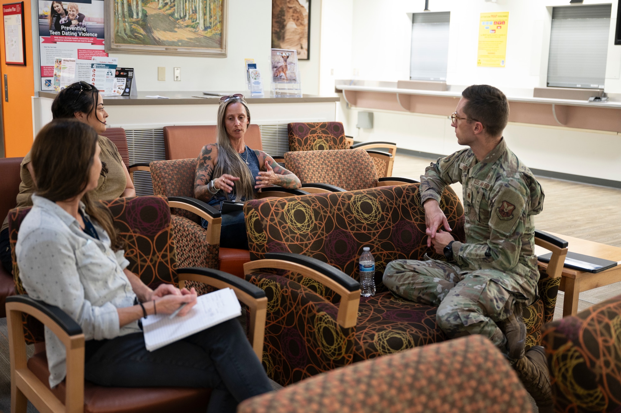 Military man in uniform sitting in waiting room talking to civilian women