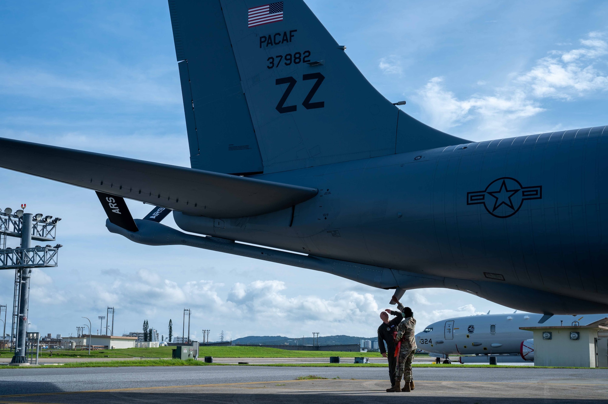 Two military members incpect the boom pod of a  KC-135 Stratotanker aircraft