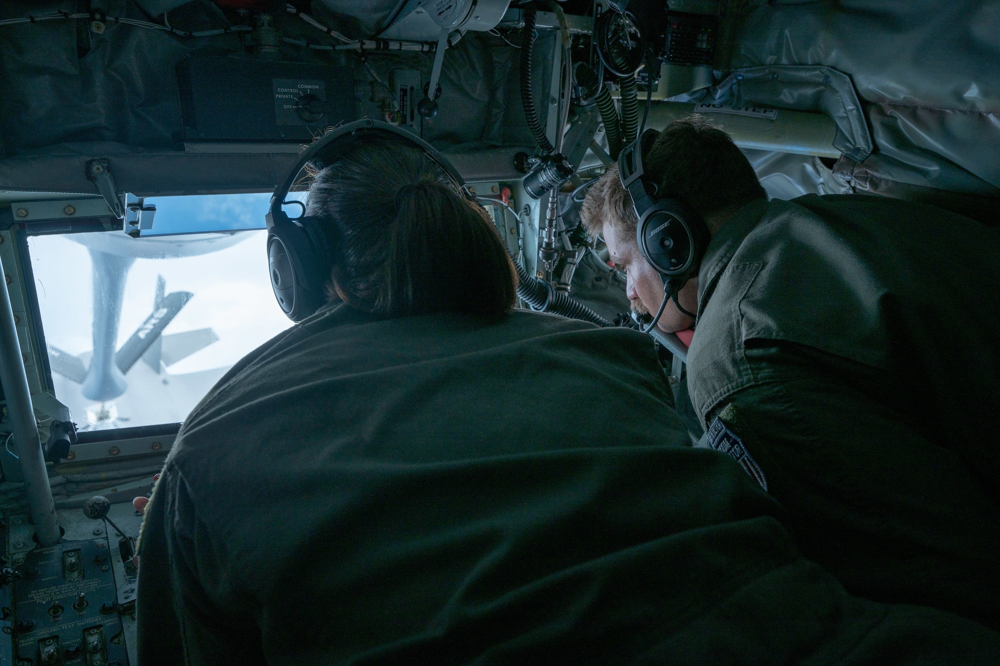two military members refill a F-35A Lightning ll inside of a boom pod in a KC-135 Stratotanker