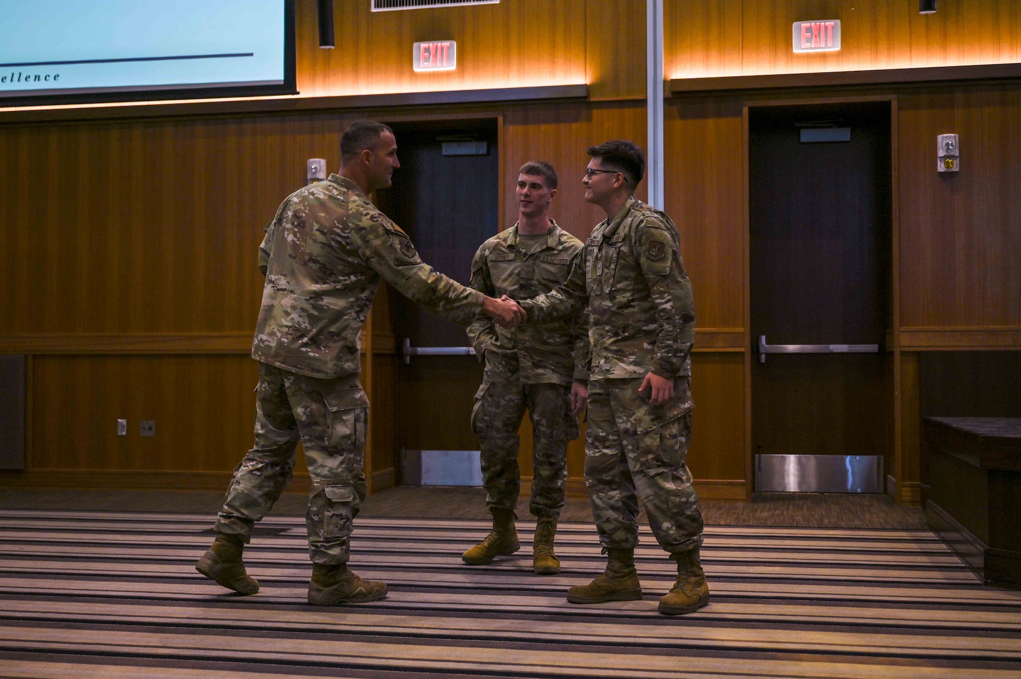 A high-ranking U.S. Air Force service member acknowledges two Airmen during a ceremony.