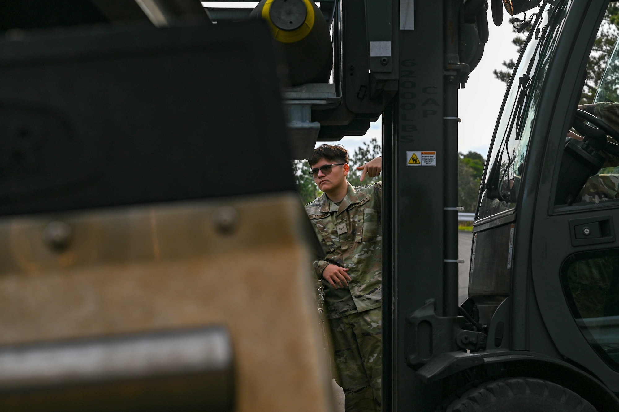 A U.S. Air Force Airman guides a forklift.