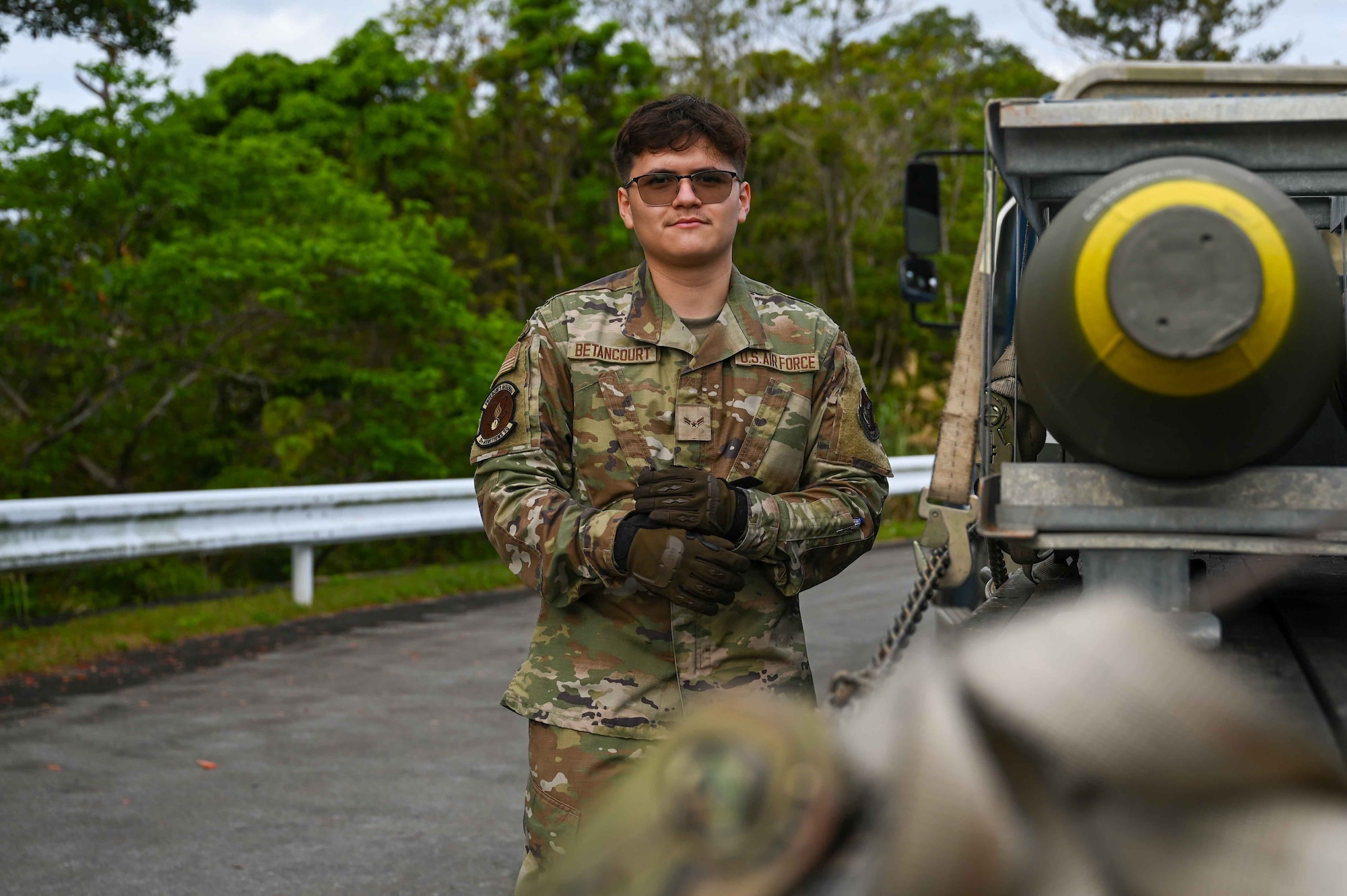 A U.S. Air Force Airman poses for a photo while leaning on a truck.