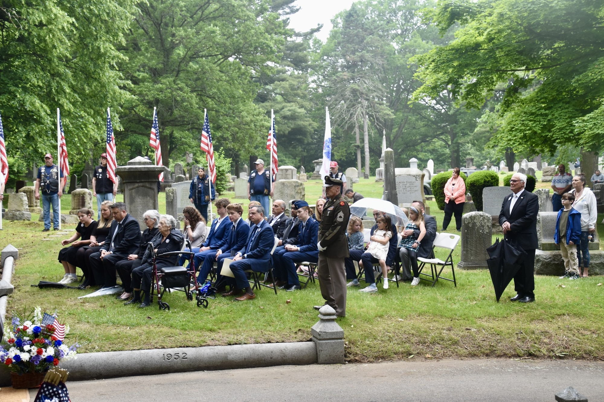 Family, citizens and uniformed personnel at funeral