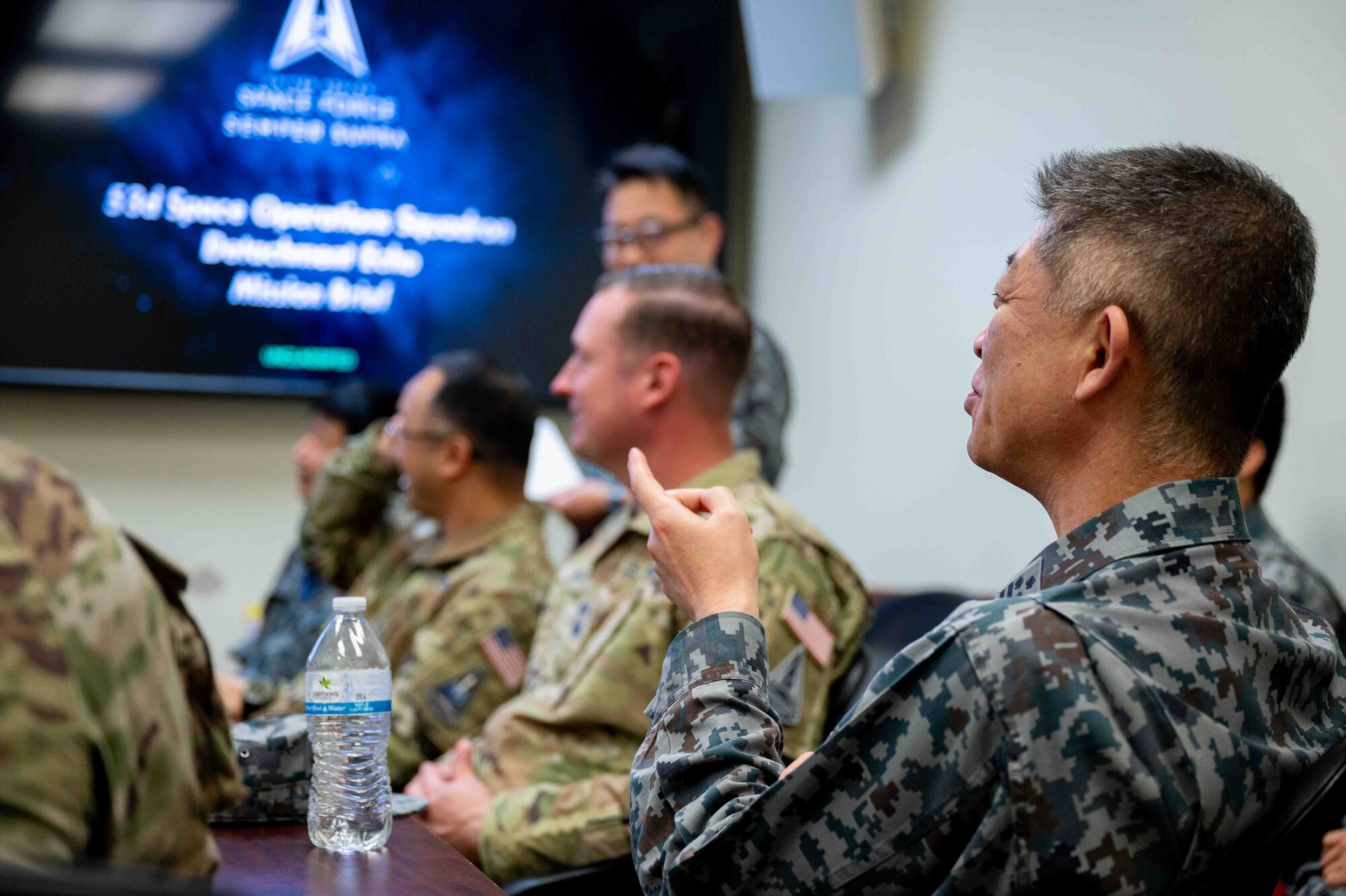 U.S. service members and Japanese service members sit a meeting together.