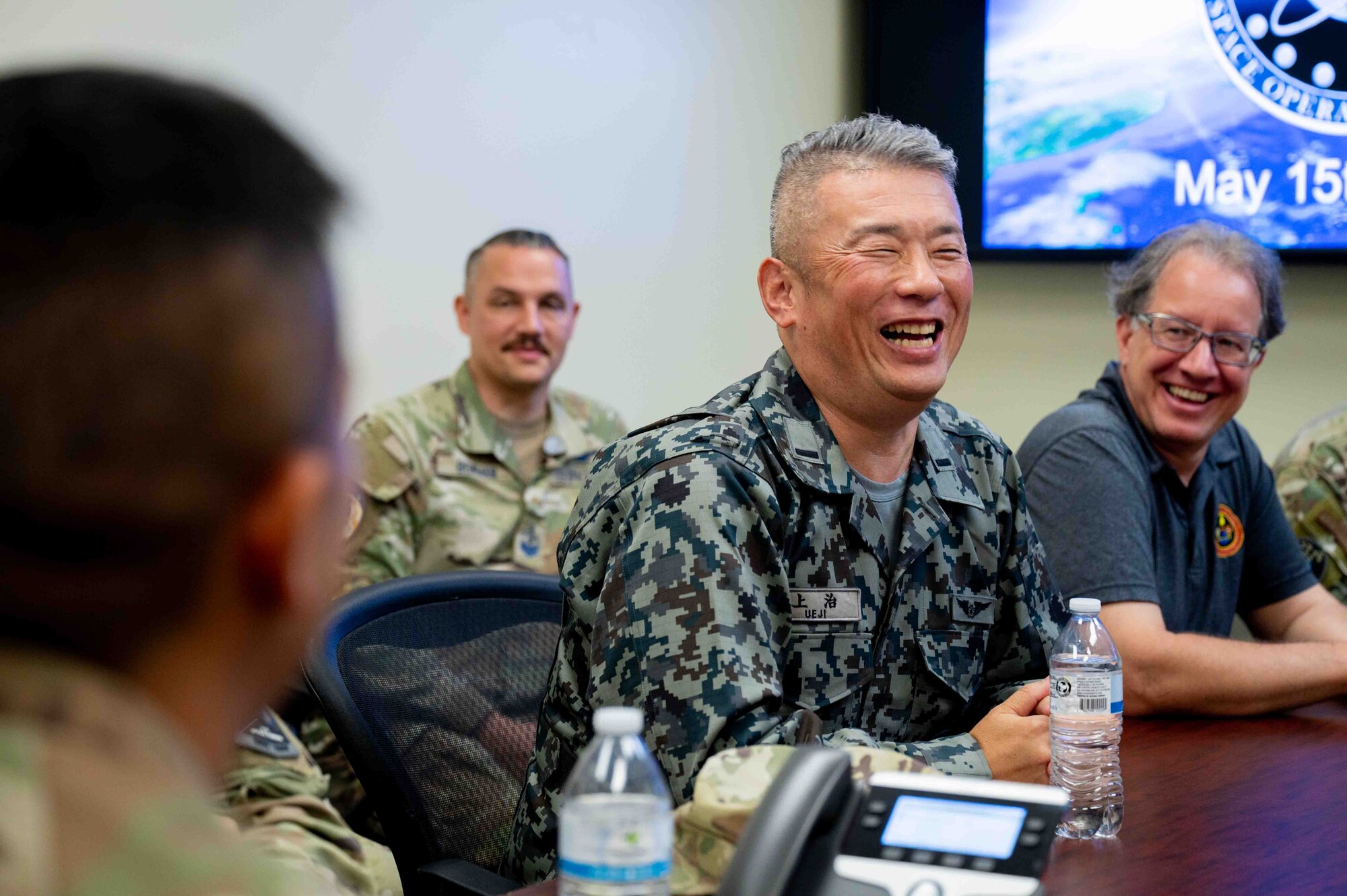 U.S. service members and Japanese service members sit in a meeting together.