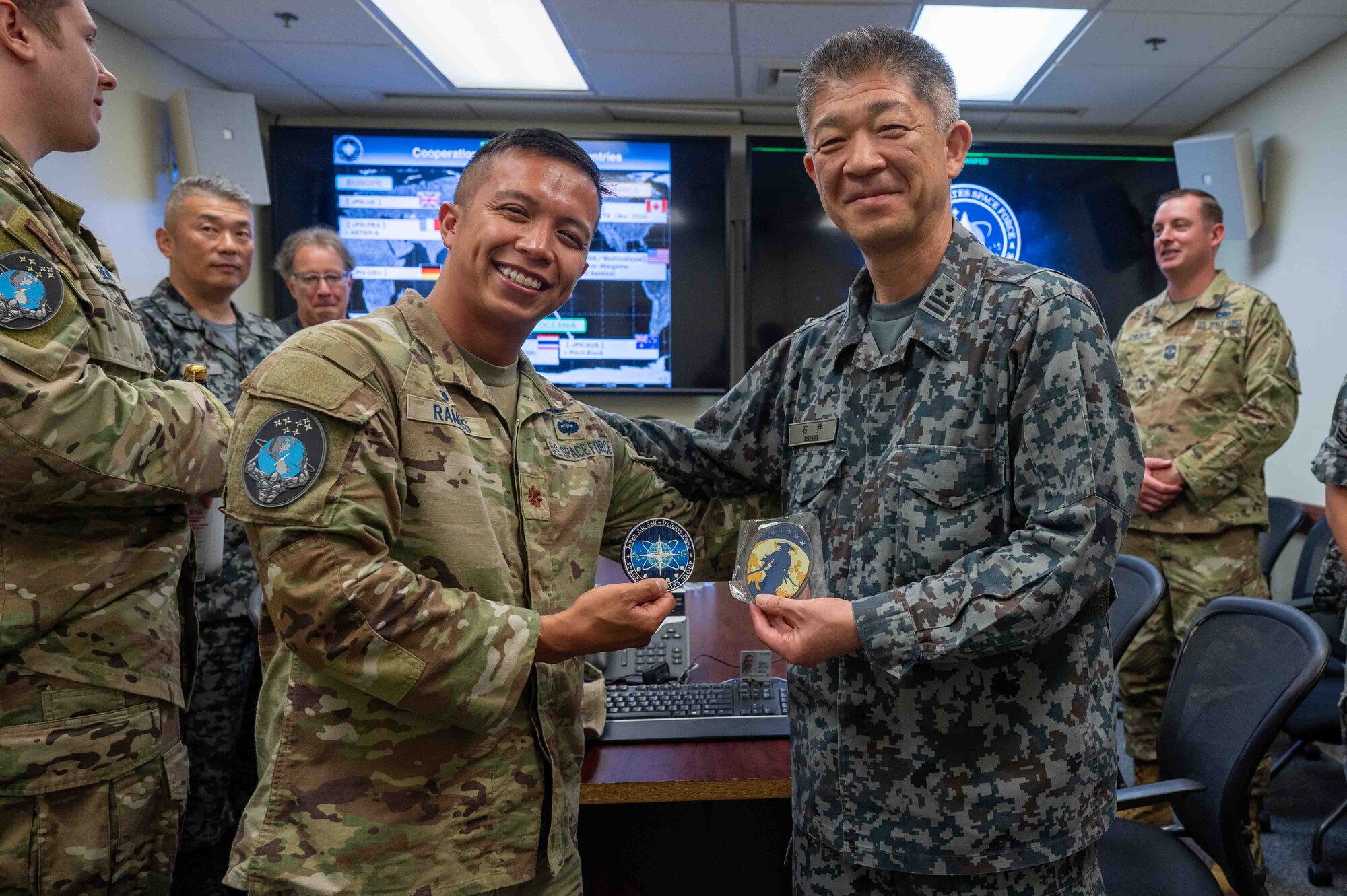 U.S. service members and Japanese service members exchange patches and pose for photos.
