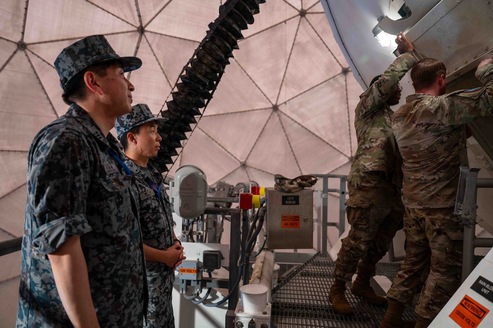 U.S. service members show equipment to Japanese service members.