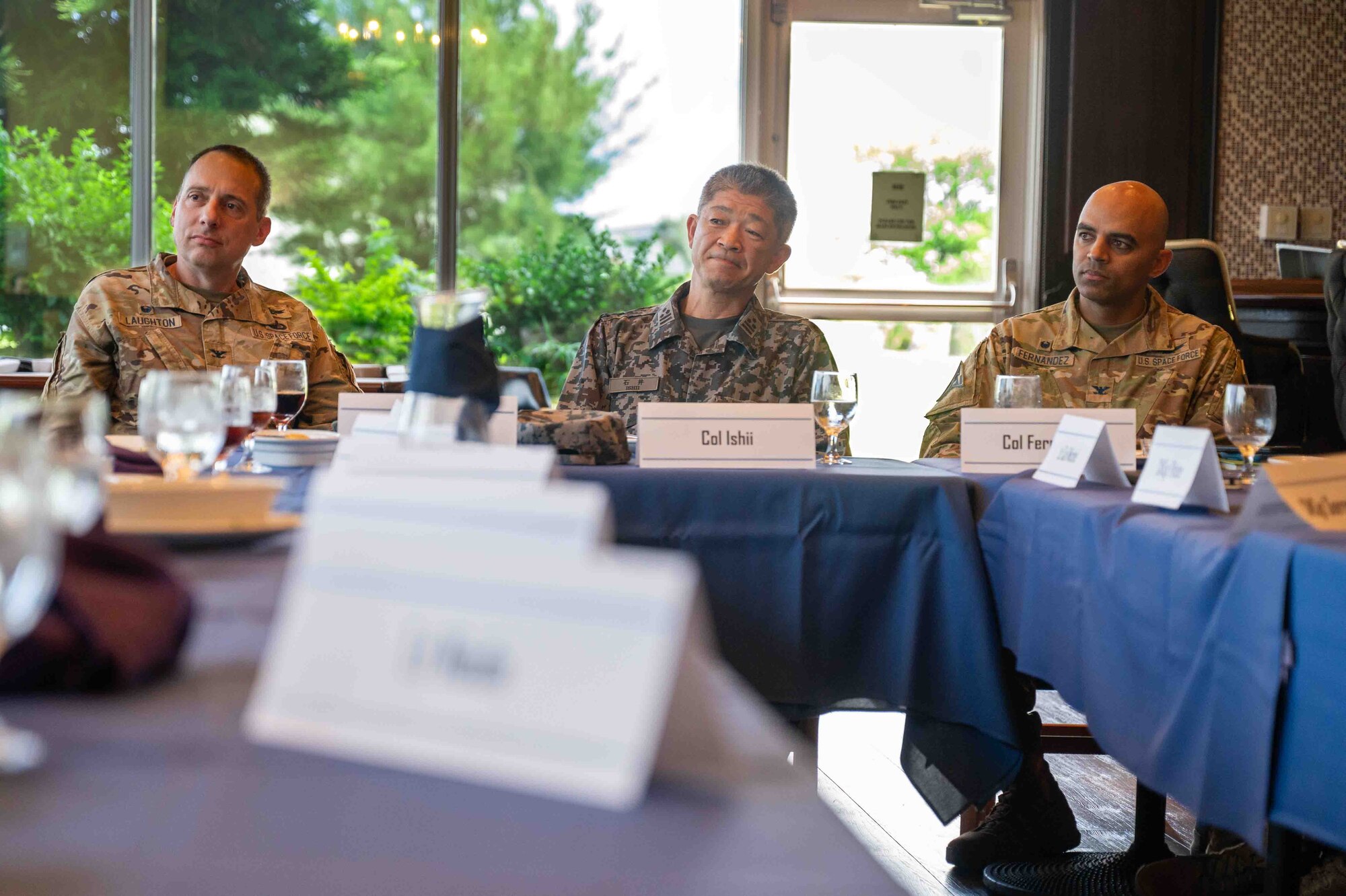 U.S. service members and Japanese service member sit next to each other at a table.