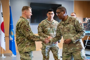 U.S. Air Force Senior Airman Michael Harmon, 731st Air Mobility Squadron aircraft services technician, receives a coin from Gen. Randall Reed, U.S. Transportation Command commander, during his visit to Osan Air Base, Republic of Korea, June 10, 2025.