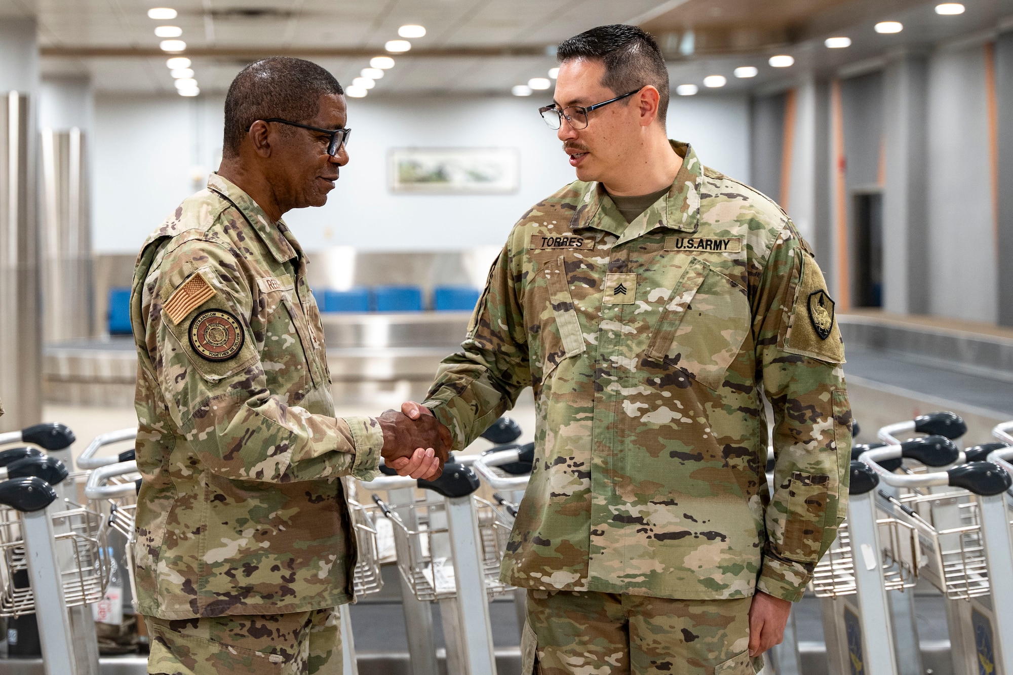 U.S. Army Sgt. David Torres, U.S. Transportation Command  J3-C defense courier, receives a coin from Gen. Randall Reed, USTRANSCOM commander, during his visit to Osan Air Base, Republic of Korea, June 10, 2025.