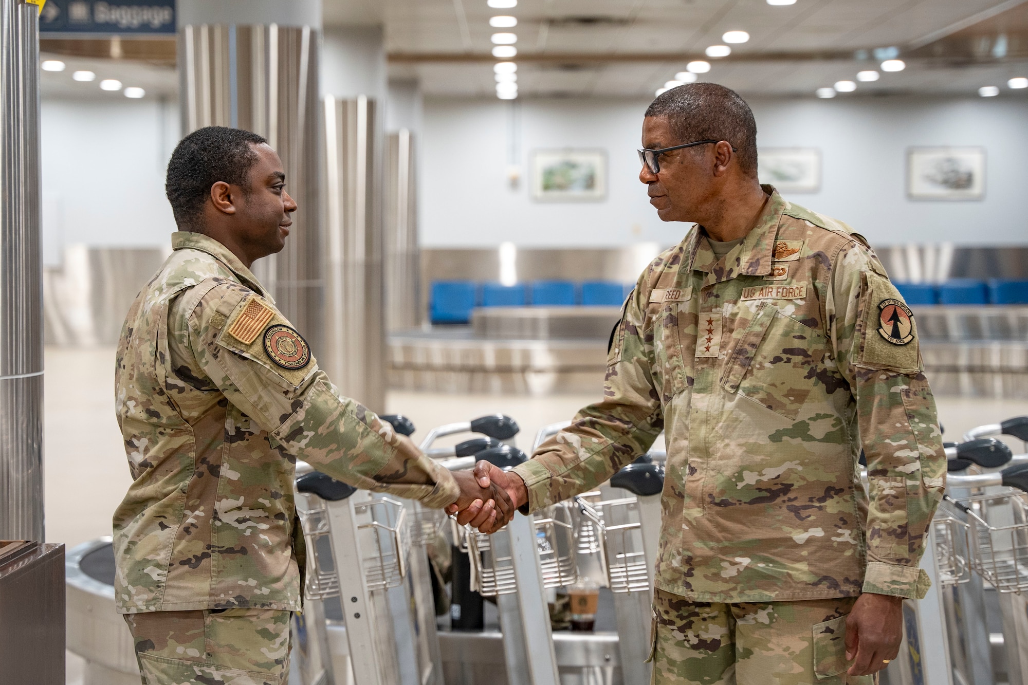 U.S. Air Force Staff Sgt. Taylor Hardman, U.S. Transportation Command J3-C defense courier, receives a coin from Gen. Randall Reed, USTRANSCOM commander, during his visit to Osan Air Base, Republic of Korea, June 10, 2025.