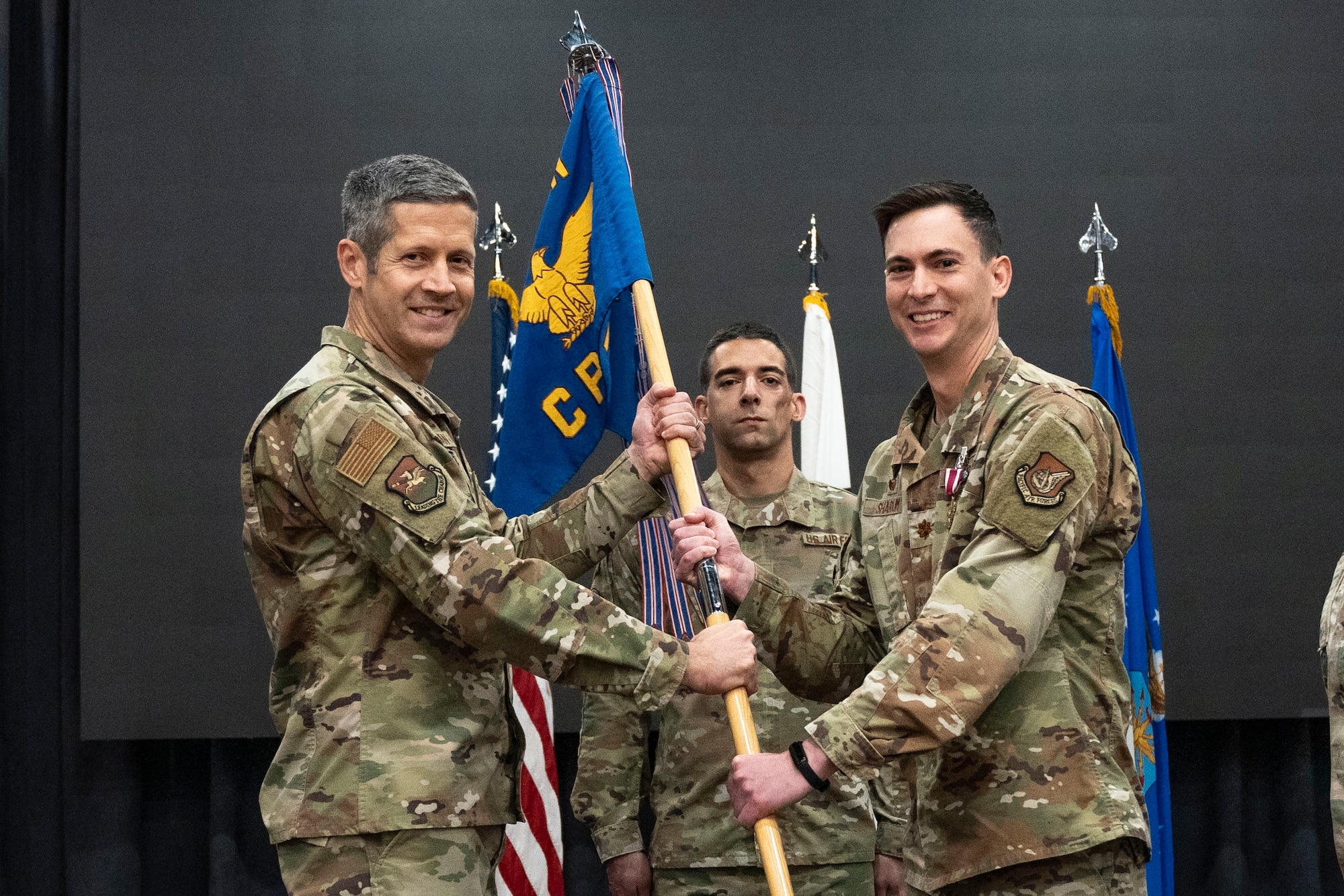 U.S. Air Force Col. William McKibban, left, 51st Fighter Wing commander, receives the guidon from Maj. Clayton Sharum, right, outgoing 51st Comptroller Squadron commander, at Osan Air Base, Republic of Korea, June 13, 2025.