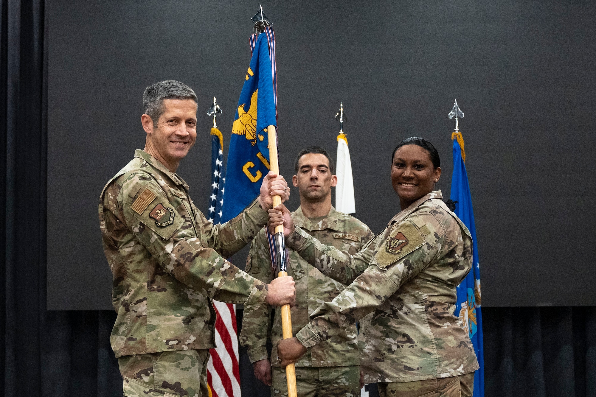 U.S. Air Force Col. William McKibban, left, 51st Fighter Wing commander, receives the guidon, passes the guidon to Maj. Kristal Wong, incoming 51st Comptroller Squadron commander, at Osan Air Base, Republic of Korea, June 13, 2025.