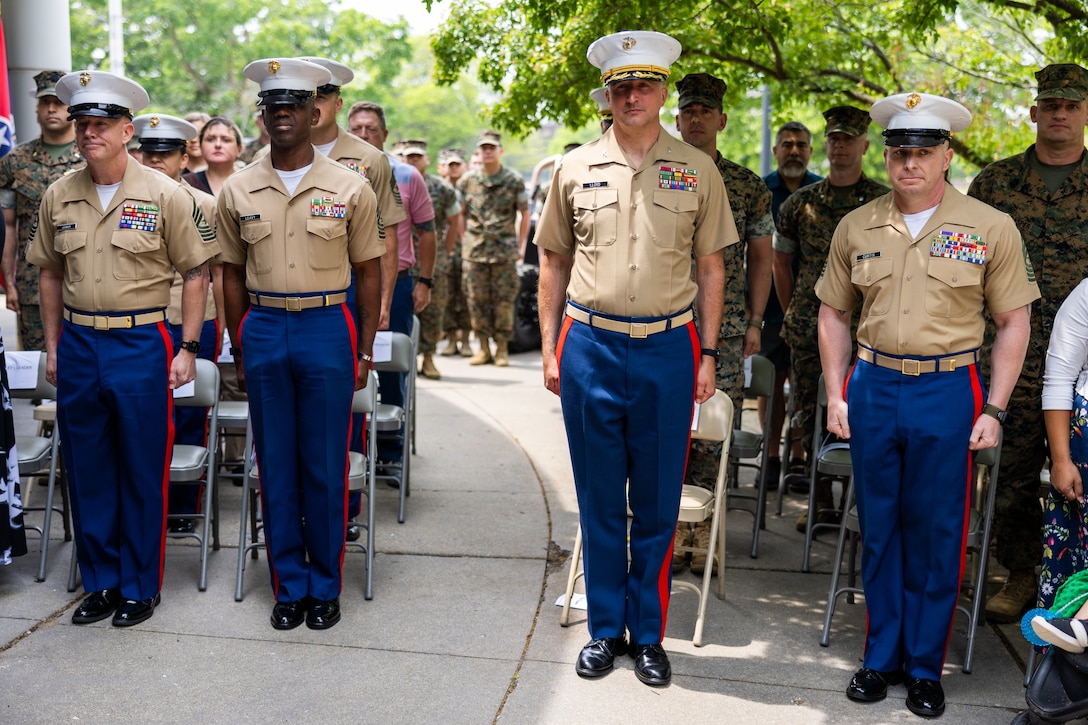 U.S. Marines with 9th Marine Corps District stand at attention for the playing of anchors’ aweigh during a post and relief ceremony at the 9th Marine Corps District Headquarters on Naval Station Great Lakes, Illinois, June 12, 2025. The ceremony  was held to mark the transition between senior enlisted leadership, signifying all responsibilities and authorities being transferred between the sergeants major. During the ceremony, Leader relinquished his post, and Sgt. Maj. Cory Curtis assumed his duties as the command’s senior enlisted leader. (U.S. Marine Corps photo by Cpl. Maxwell Cook)