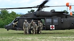 Three uniformed service members run out of helicopter.