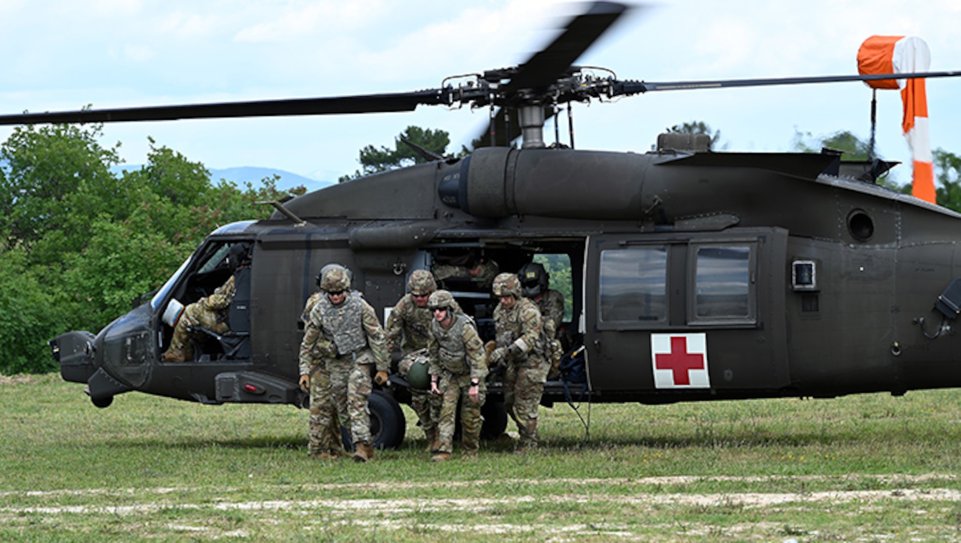 Three uniformed service members run out of helicopter.