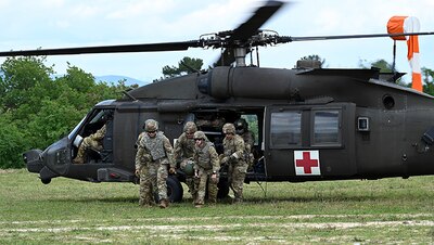 Three uniformed service members run out of helicopter.