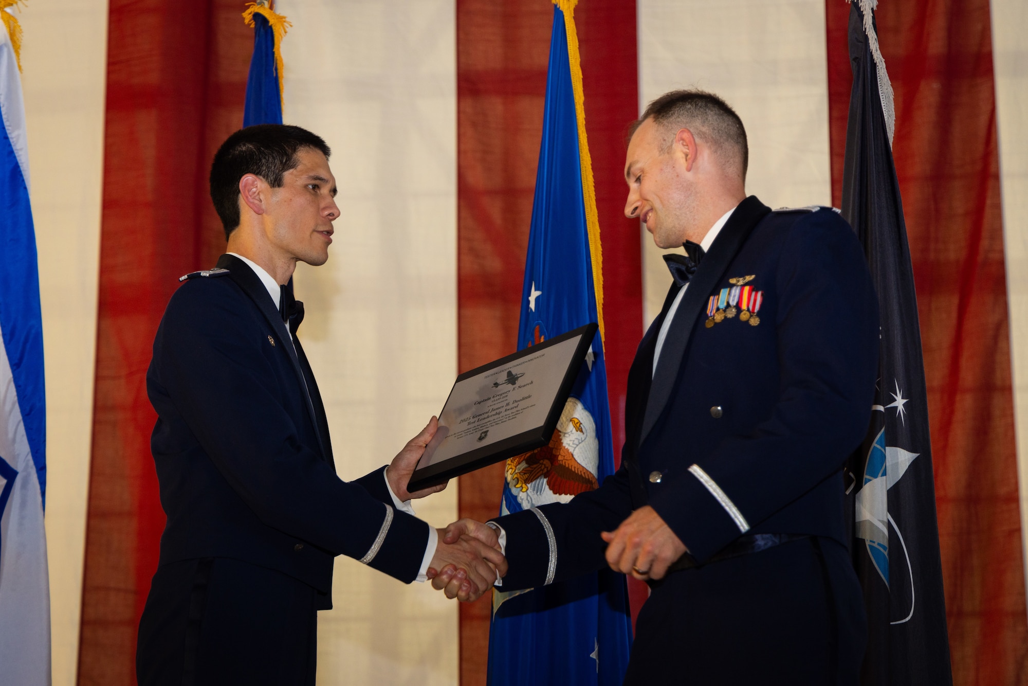 Col. James Valpiani, commandant, Air Force Test Pilot School, presents school alumni Capt. Gregory Search, graduate of Class 22B, with the inaugural Doolittle Test Leadership Award, during school graduation at Edwards Air Force Base, CA.

Named in honor of Gen. James "Jimmy" Doolittle, the famed Air Force pioneer and former chief test pilot of the Army Air Corps, the award recognizes a recent TPS graduate who best exemplifies the four pillars of the school's vision: "tester, leader, thinker, innovator." Capt. Search currently serves as Assistant Director of Operations at the 452nd Flight Test Squadron at Edwards Air Force Base. In this role, he leads multi-billion-dollar test programs with significant strategic impact and has trailblazed the development of cutting-edge autonomous aircraft. (Air Force photo by Brandon Hernandez)