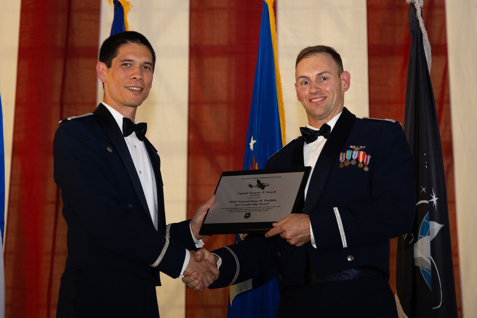 Col. James Valpiani, commandant, Air Force Test Pilot School, presents school alumni Capt. Gregory Search, graduate of Class 22B, with the inaugural Doolittle Test Leadership Award, during school graduation at Edwards Air Force Base, CA. Named in honor of Gen. James "Jimmy" Doolittle, the famed Air Force pioneer and former chief test pilot of the Army Air Corps, the award recognizes a recent TPS graduate who best exemplifies the four pillars of the school's vision: "tester, leader, thinker, innovator." Capt. Search currently serves as Assistant Director of Operations at the 452nd Flight Test Squadron at Edwards Air Force Base. In this role, he leads multi-billion-dollar test programs with significant strategic impact and has trailblazed the development of cutting-edge autonomous aircraft. (Air Force photo by Brandon Hernandez)