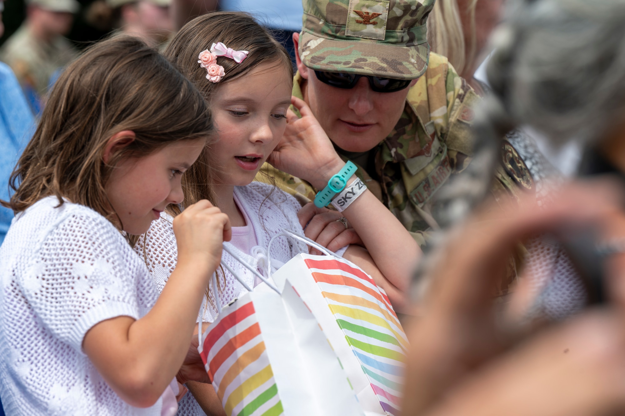 Family members of U.S. Air Force Lt. Col. Daniel P. Boyarski, 794th Communications Squadron outgoing commander, peer into a bag containing a gift bestowed by Boyarski during the 794th CS change of command ceremony at Joint Base Anacostia-Bolling, Washington, D.C., June 10, 2025. Boyarski highlighted the support and sacrifice from his family that contributed to mission success. (U.S. Air Force photo by Hayden Hallman)