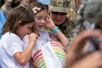 Family members of U.S. Air Force Lt. Col. Daniel P. Boyarski, 794th Communications Squadron outgoing commander, peer into a bag containing a gift bestowed by Boyarski during the 794th CS change of command ceremony at Joint Base Anacostia-Bolling, Washington, D.C., June 10, 2025. Boyarski highlighted the support and sacrifice from his family that contributed to mission success. (U.S. Air Force photo by Hayden Hallman)