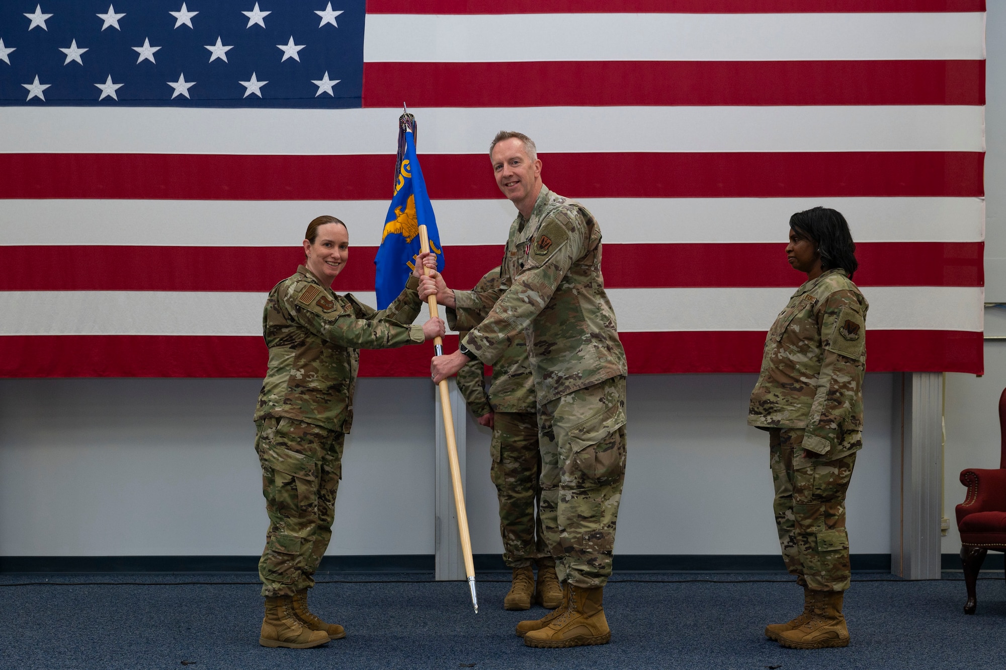 Lt. Col. Thomas Naughton, 319th Healthcare Operations Squadron out-going commander, passes the guidon to Col. Deana Dominguez, 319th Medical Group commander, signifying his relinquishing of command during a change of command ceremony at Grand Forks Air Force Base, N.D., June 10, 2025.
