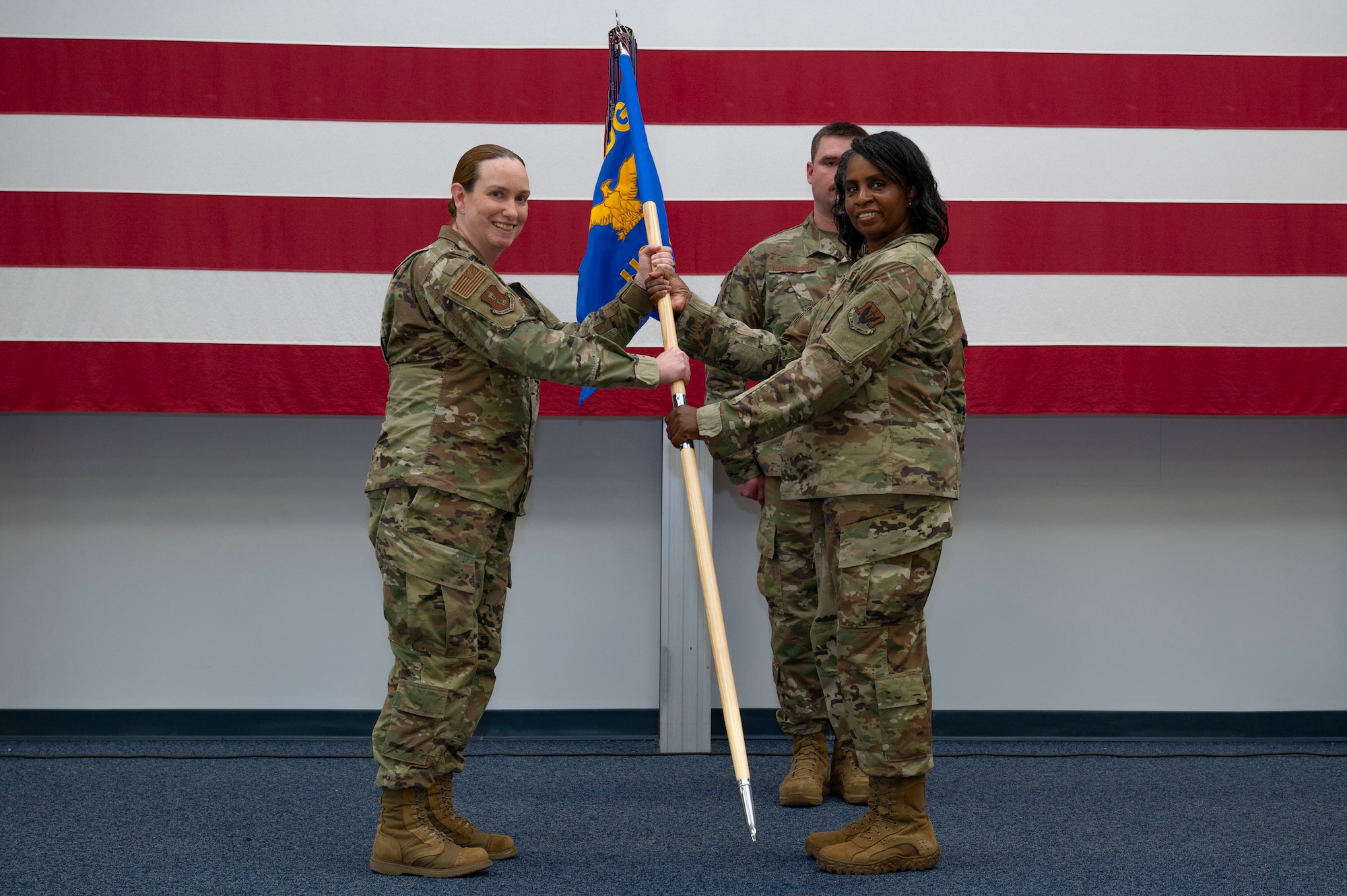 Col. Deana Dominguez, 319th Medical Group commander, passes the guidon to Lt. Col. Tammy Shy, 319th HCOS incoming commander, during a change of command ceremony at Grand Forks Air Force Base, N.D., June 10, 2025.
