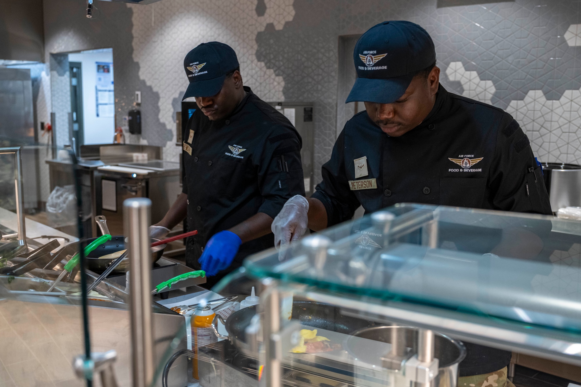 U.S. Air Force Airman 1st Class Andrez Brewster, 49th Force Support Squadron food service apprentice, left, makes pasta with U.S. Air Force Airman Israel Peterson, 49th FSS food service apprentice, during the Shifting Sands Dining Facility grand reopening ceremony at Holloman Air Force Base, New Mexico, June 12, 2025.