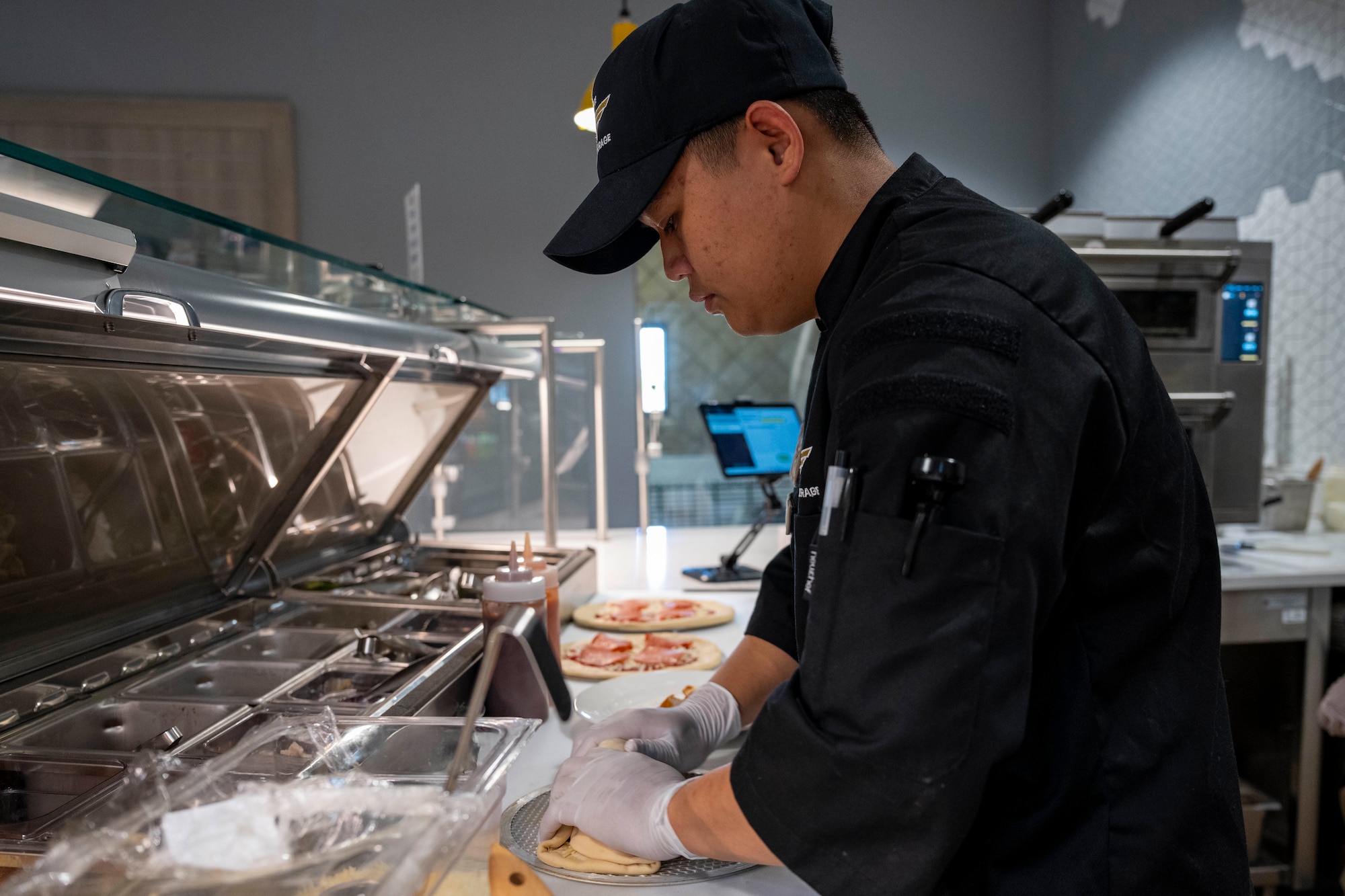 U.S. Air Force Airman 1st Class Ezhion Fumar, 49th Force Support Squadron food services apprentice, makes a pizzarito during the Shifting Sands Dining Facility grand reopening ceremony at Holloman Air Force Base, New Mexico, June 12, 2025.