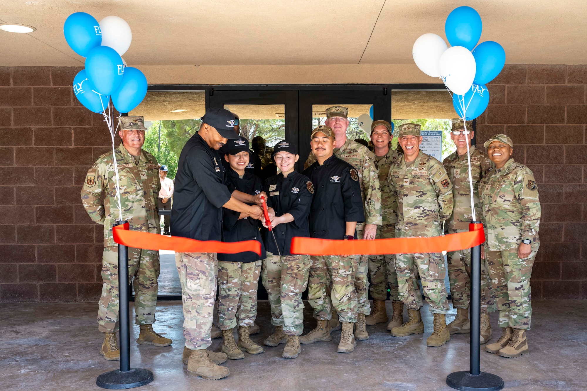 49th Wing leadership, 49th Force Support Squadron members and members of Air Force Services Center leadership, cut a ribbon during the Shifting Sands Dining Facility grand reopening ceremony at Holloman Air Force Base, New Mexico, June 12, 2025.