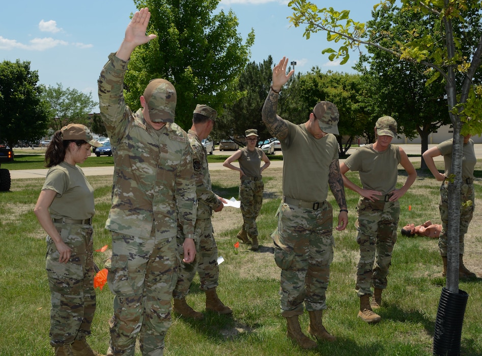 Airmen of the 185th Force Support Squadron stand in line horizontally with each other. Two raise their hands.