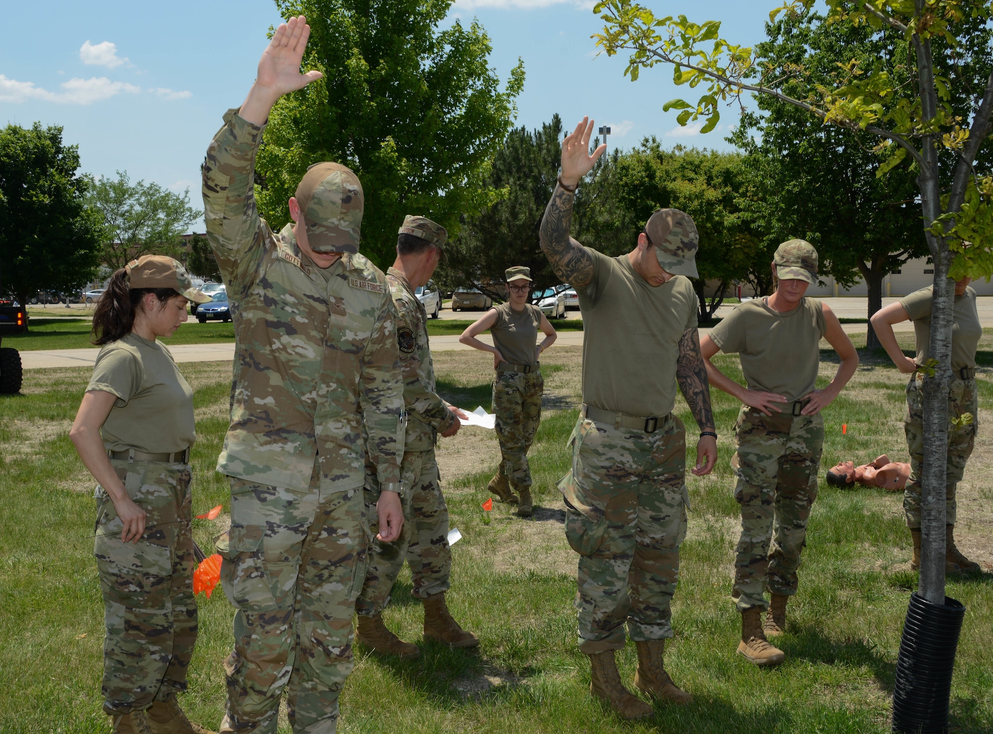 Airmen of the 185th Force Support Squadron stand in line horizontally with each other. Two raise their hands.