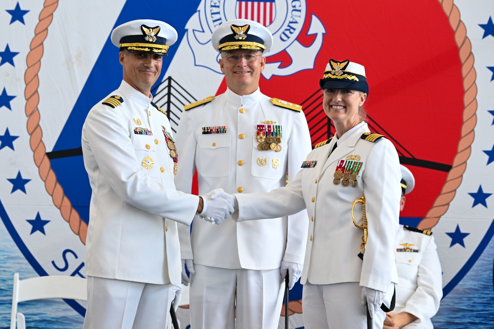 Capt. Michael Kahle (left) shakes hands with Capt. Courtney Sergent (right) during a change of command ceremony held at the Port of Tampa Bay in Tampa, Florida, June 13, 2025. Rear Adm. Douglas Schofield, commander of the Seventh Coast Guard District, presided over the ceremony. (U.S. Coast Guard photo by Petty Officer 1st Class Riley Perkofski)