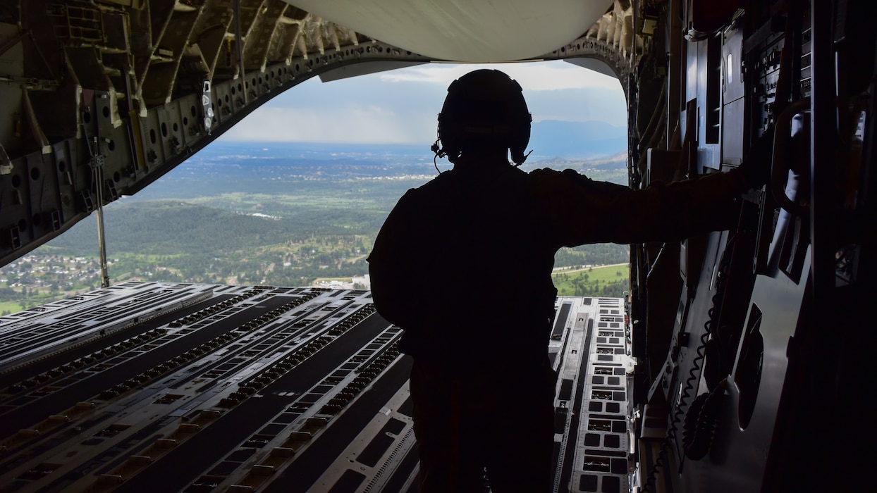 A U.S. Air Force loadmaster views the ground from the cargo bay of a C-17