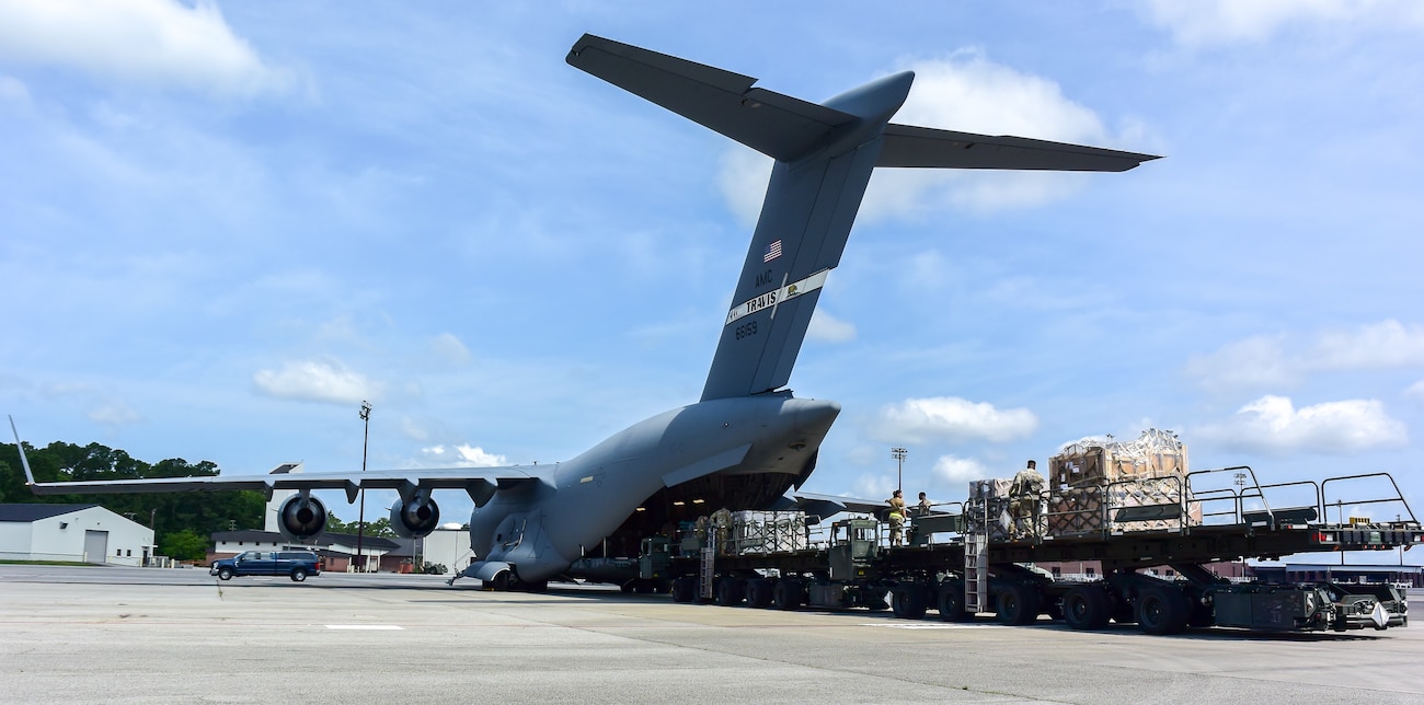 Multiple airmen push cargo onto C-17
