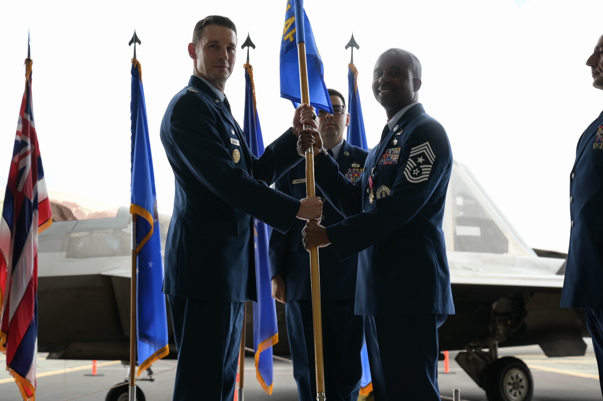 A USAF Colonel hands a guidon to a USAF command chief.