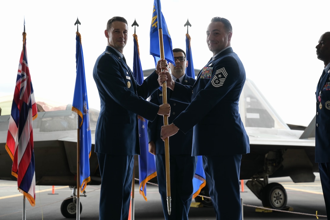 A USAF Colonel hands a guidon to a USAF command chief.