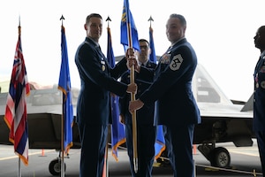 A USAF Colonel hands a guidon to a USAF command chief.