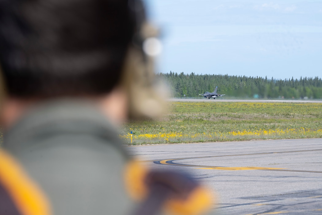 U.S. Senior Airman Landon Gunsauls, 8th Fighter Wing Public Affairs journeyman, watches a F-16 Fighting Falcon from the 80th Fighter Squadron taxi down the runway at Eielson Air Force Base, Alaska, June 13, 2025.