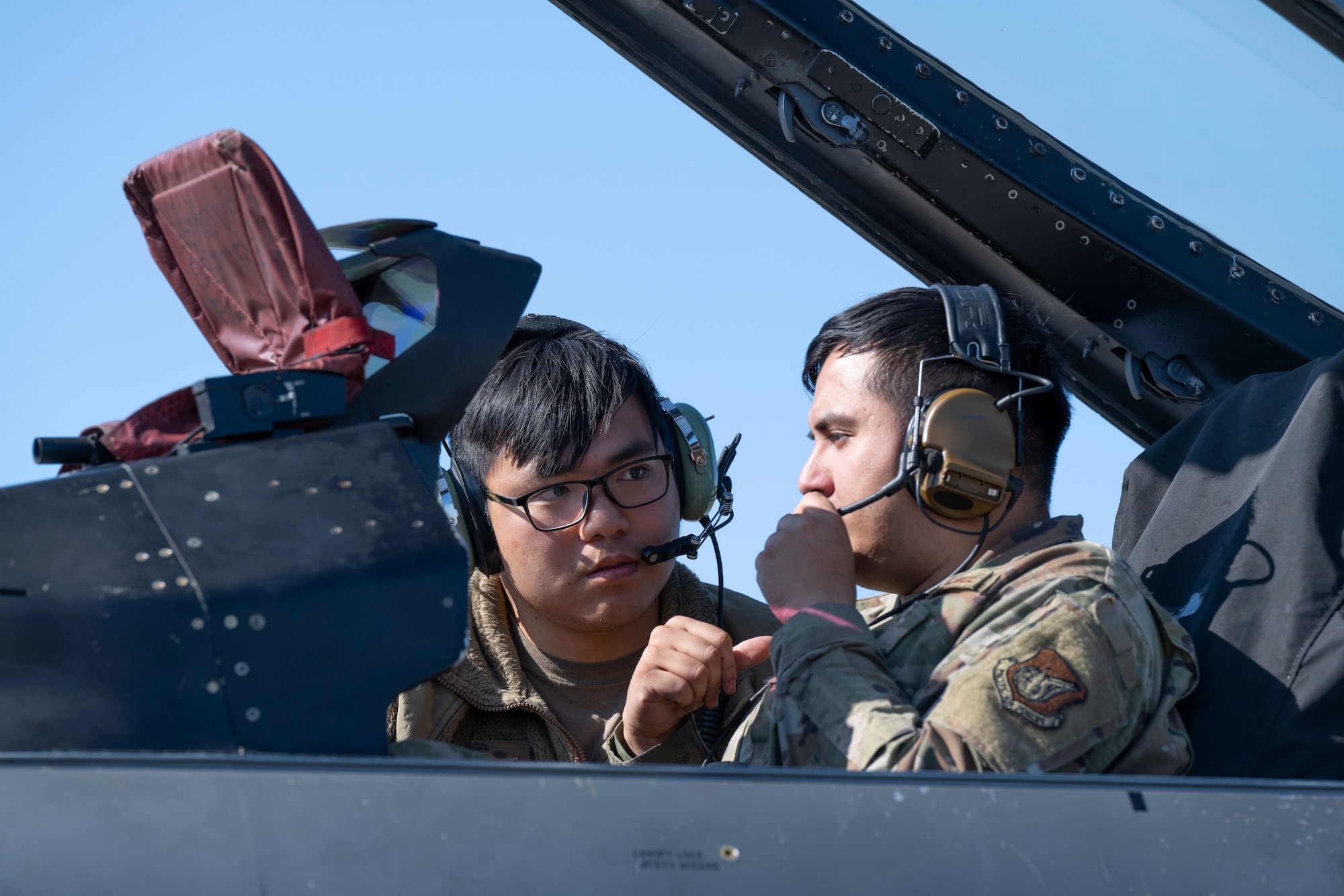 U.S. Air Force Senior Airman Alan Costanzo, left, 35th Fighter Generation Squadron avionics journeyman, and Staff Sgt. Erik Reynolds, 35th FGS avionics craftsman, discuss maintenance inside the cockpit of an F-16 Fighting Falcon during Red Flag-Alaska 25-2 at Eielson Air Force Base, Alaska, June 13, 2025.
