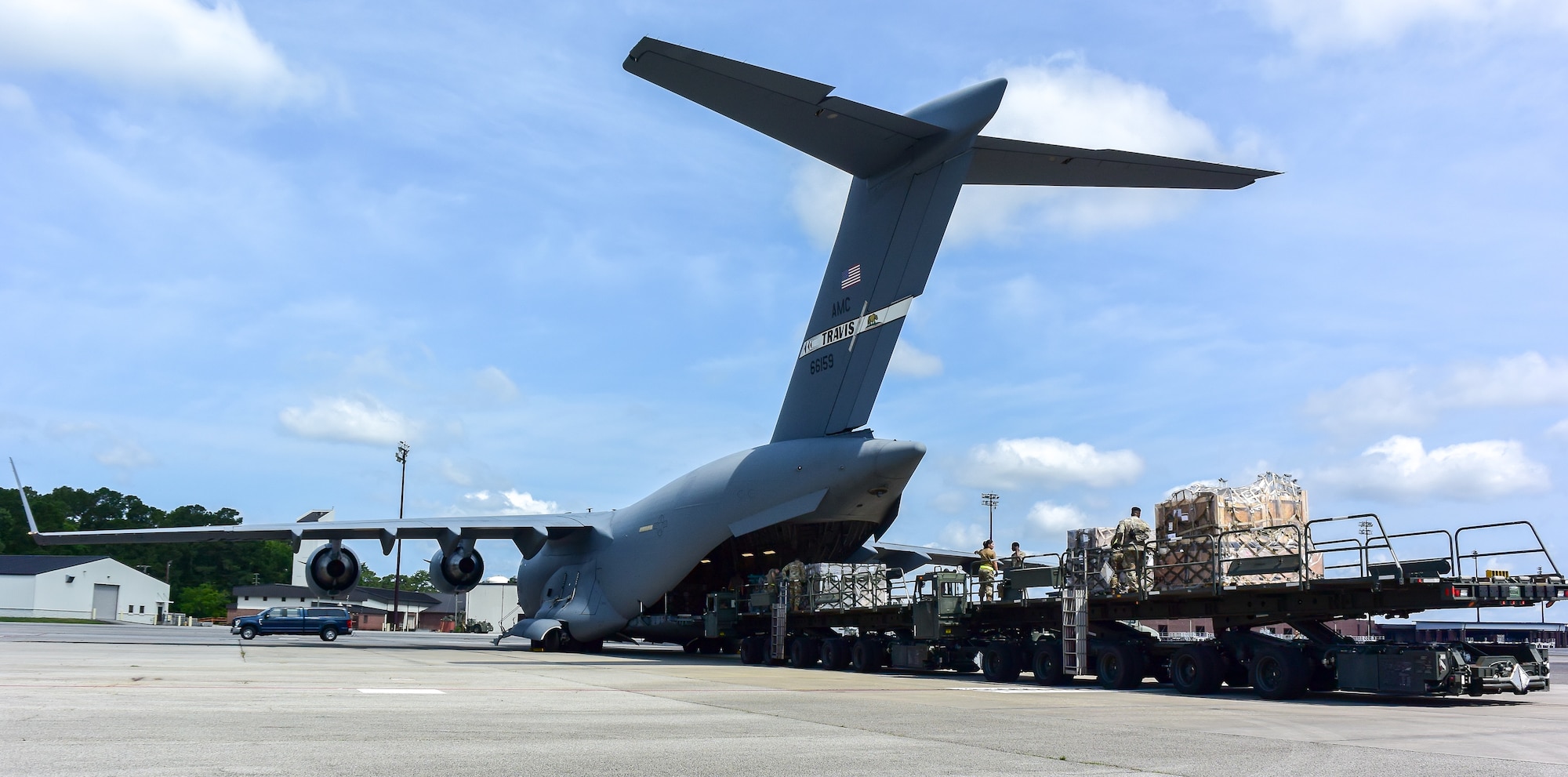 Multiple airmen push cargo onto C-17