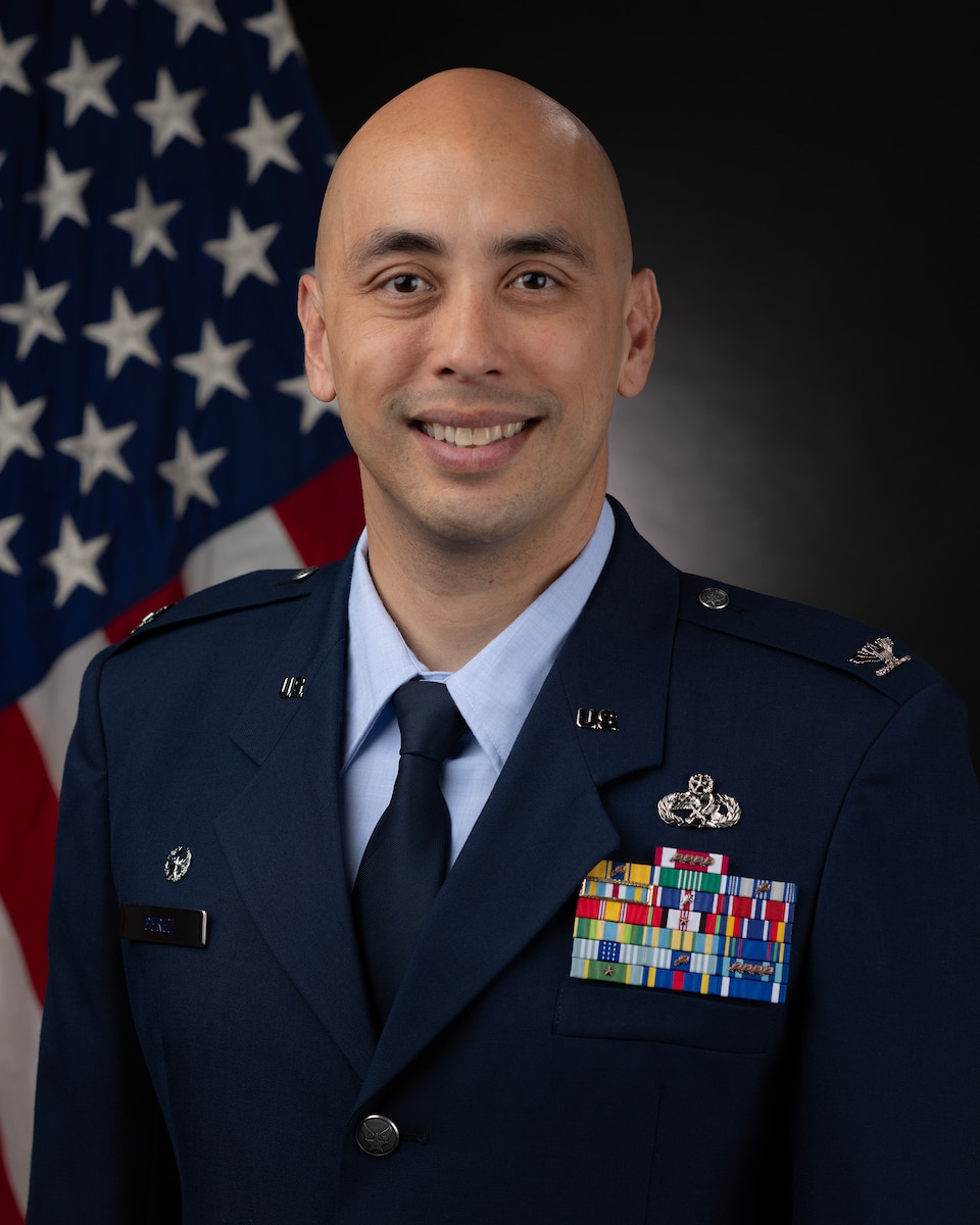 An air force biography photo with an individual in front of the U.S. flag