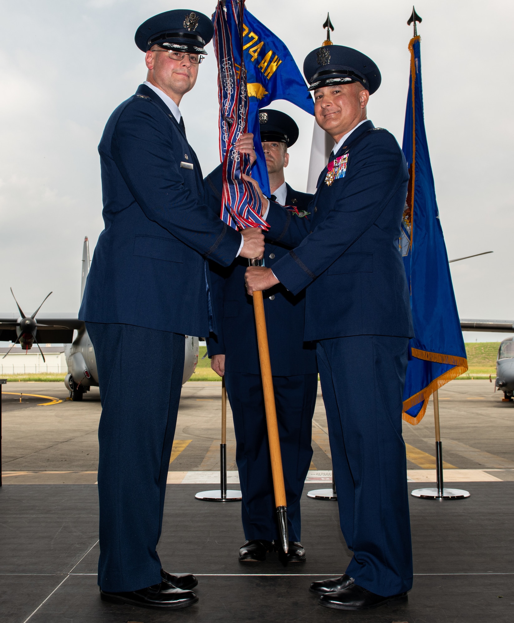 U.S. Air Force members, dressed in their blue dress uniforms, hold a colorful baton with a blue flag at the top.