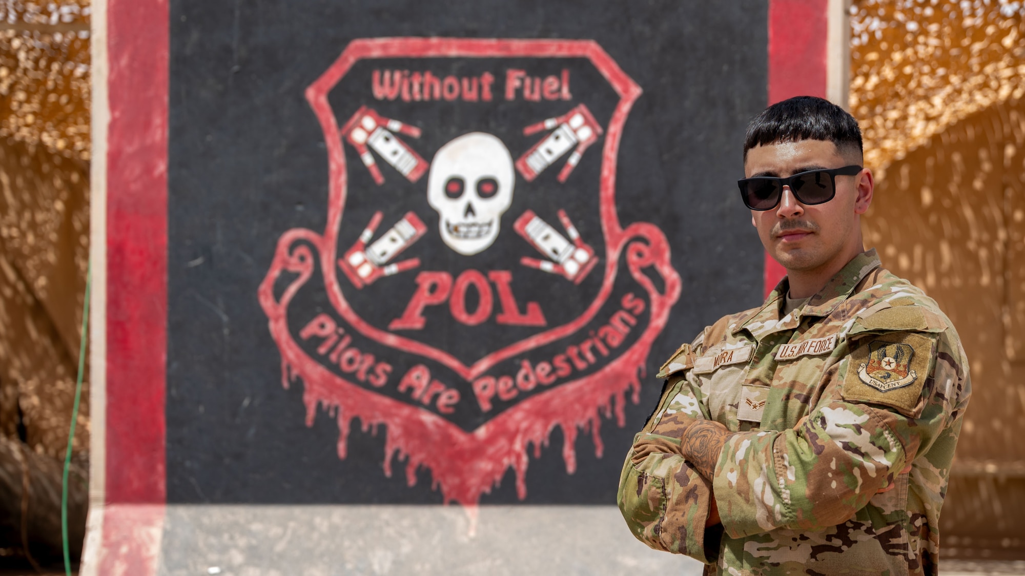 A man poses for a photo in front of a wall.