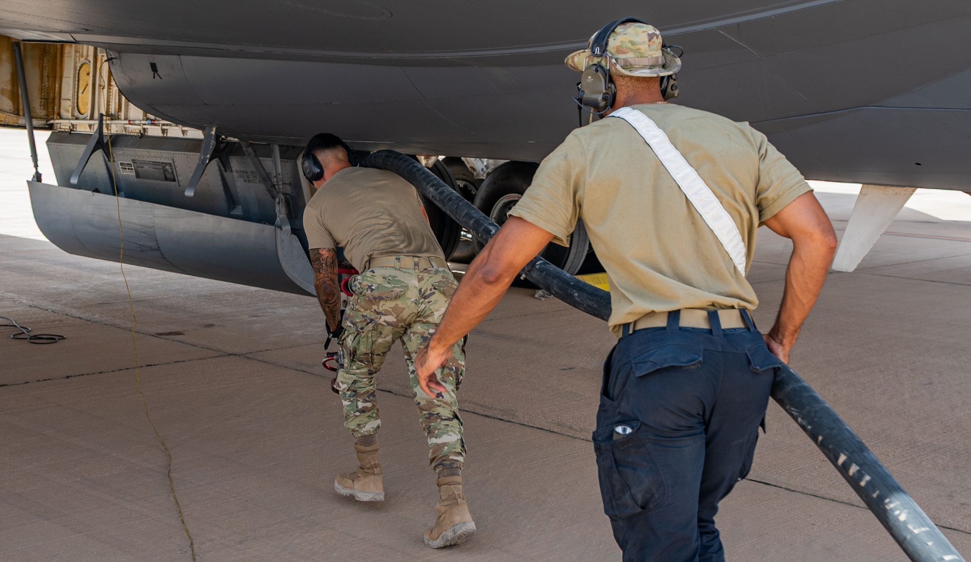 Two men drag a hose to a KC-135.