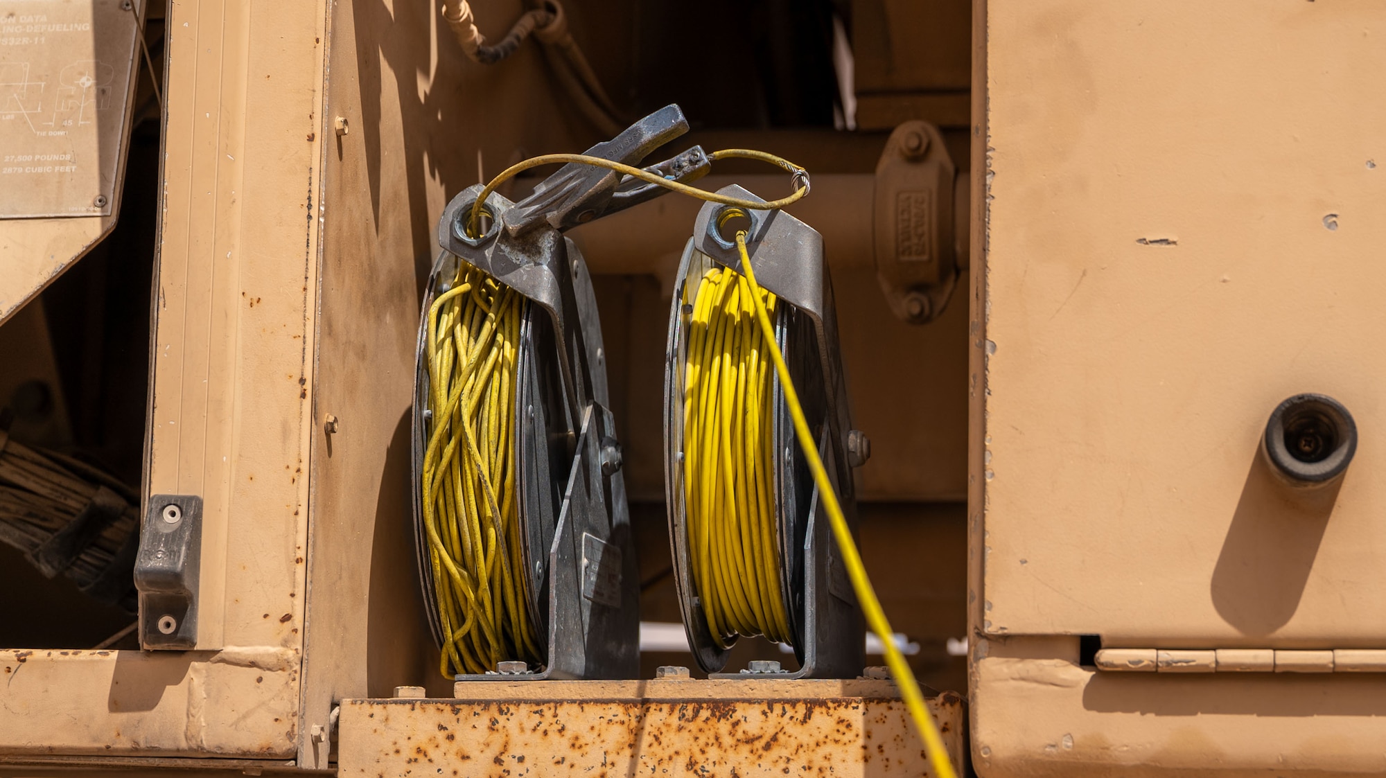 Two reels of cable sit on a fuel truck.